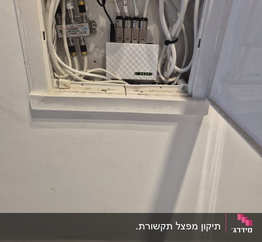 ארון תקשורת ביתי שקוע בקיר עם מתג רשת וכבלים מסודרים